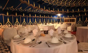 Scene-de-diner-festif-dans-une-tente-marocaine-avec-des-serveurs-en-tenue-traditionnelle