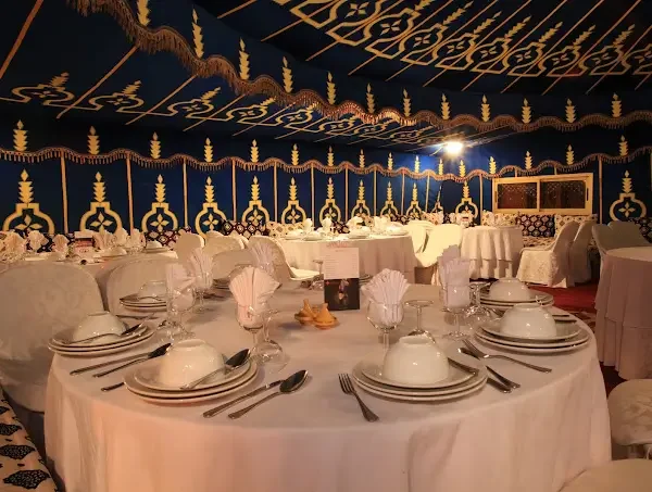Scene-de-diner-festif-dans-une-tente-marocaine-avec-des-serveurs-en-tenue-traditionnelle