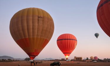 three-hot-air-balloons-are-being-prepared-for-flight-at-dawn-in-a-desert-landscape